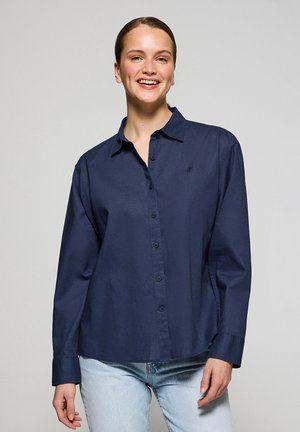 Marineblauwe button-up shirt van een zachte, gestructureerde stof. Bevat een kraag, lange mouwen en subtiele borduursels op de borst.