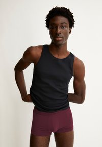 Schwarzes, geripptes Tanktop und burgunderfarbene Boxerbriefs. Der Stoff wirkt glatt und enganliegend, mit einem markierten Bund bei der Unterwäsche.