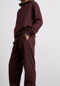 Bordový mikina s přední kapsou a odpovídajícími jogger kalhotami, s volnějším střihem, měkkou texturou a jemnými švy.