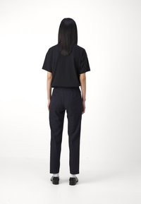 Black short-sleeve shirt and navy pants, featuring a tailored fit, with smooth fabric and minimalistic design. Black shoes complete the look.