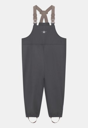 Mono impermeable gris oscuro con tirantes cruzados ajustables en color beige y puños elásticos con correas para los pies en los tobillos.