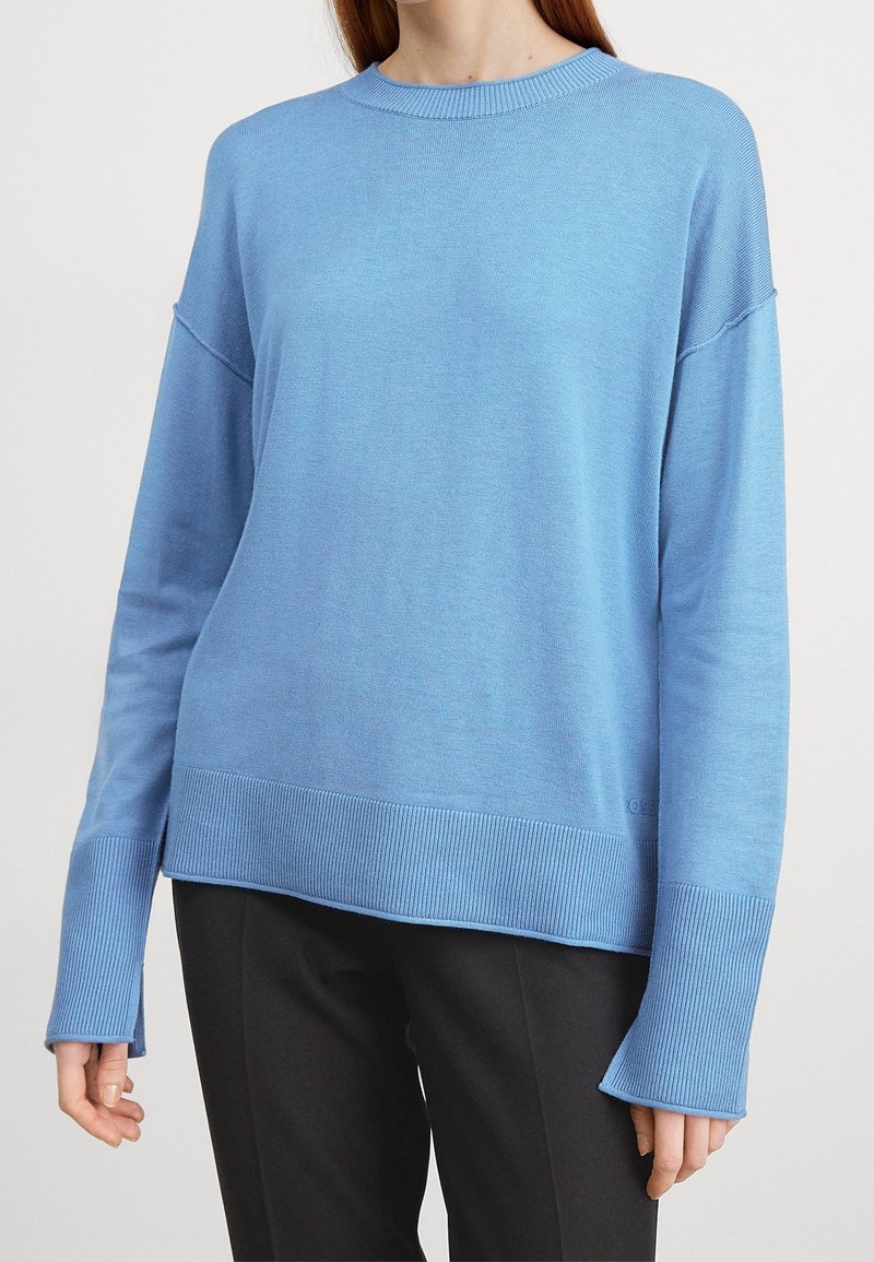 Helles blaues, gestricktes Sweatshirt mit Rundhalsausschnitt, überschnittenen Schultern sowie geripptem Saum und Bündchen. Hat einen lockeren Schnitt und eine glatte Textur.