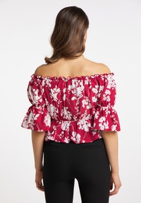 Rød blomster off-shoulder bluse med klokkeærmer, rynket halsudskæring og peplum talje. Blomsterdesign i hvid; tekstureret bomuldsstof.