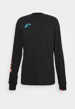 T-shirt noir à manches longues Nike avec petit logo bleu sur la poitrine et motifs graphiques roses le long de la manche droite sur un fond uni.