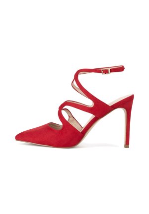 Zapato de tacón alto de ante rojo con puntera afilada, tiras en el tobillo y diseño recortado. El tacón es delgado y con forma cónica. Presenta un acento de hebilla dorada.