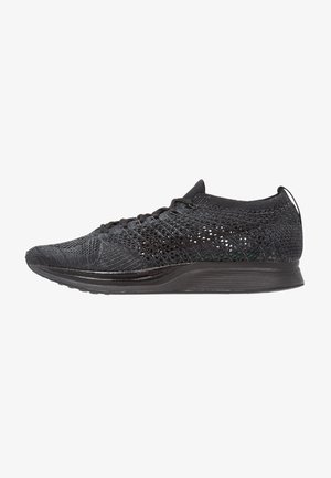 Czarny niski sportowy sneaker z dzianą siateczką na wierzchu, sznurówkami i miękką podeszwą, pokazany w profilu z boku zwrócony w prawo.