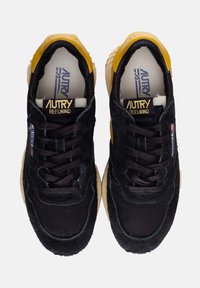 Sneakers neri e gialli con superiore in suede e rete, dettagli testurizzati, lacci piatti e suola in gomma beige.