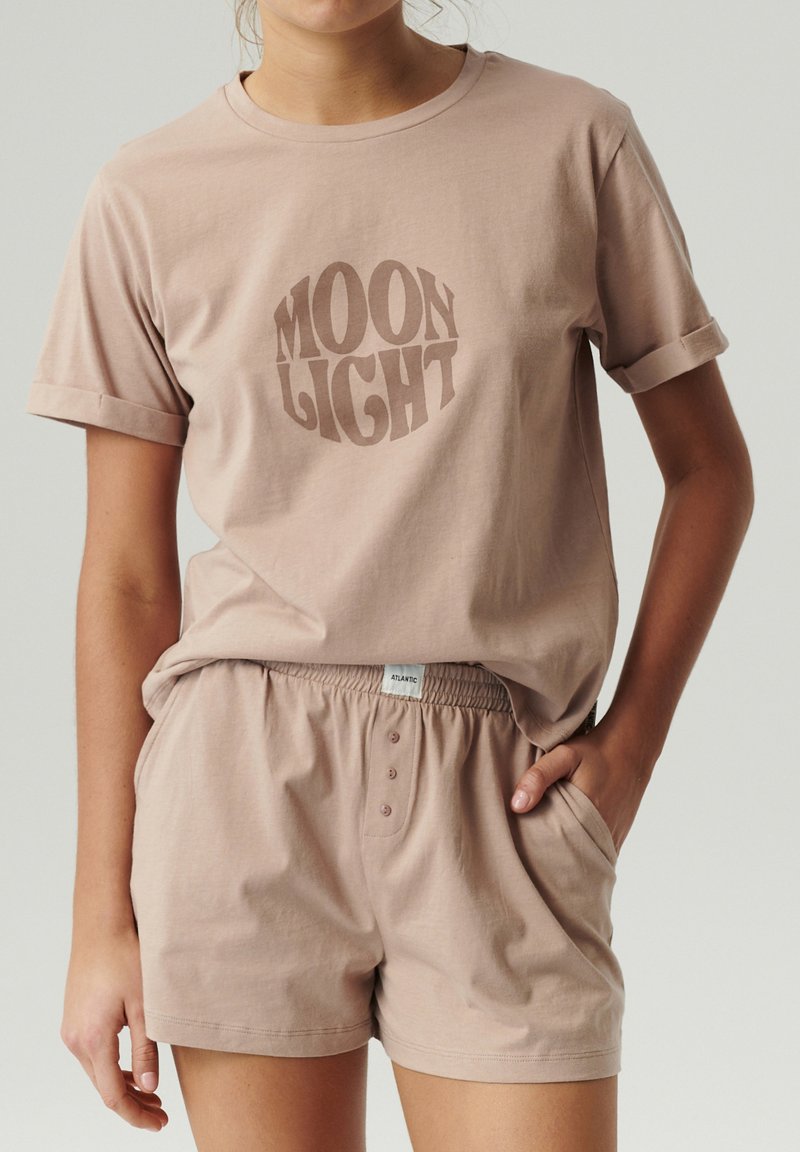 Jasnoróżowa bawełniana koszulka z podwiniętymi rękawami z logo "MOON LIGHT", zestawiona z dopasowanymi bawełnianymi szortami z elastycznym paskiem i guzikami.