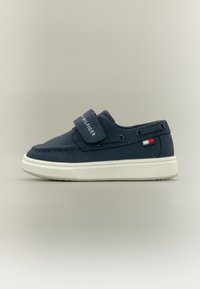 Ναυτικού μπλε παπούτσια slip-on από μαλακό υλικό, με ιμάντα Velcro και λευκή σόλα. Διαθέτουν μικρή κόκκινη και λευκή λεπτομέρεια λογότυπου.