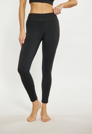 Schwarze Leggings mit hohem Taillenbund, glatter Textur und einer taillierten Passform, die an den Knöcheln enger wird. Keine sichtbaren Muster oder Beschläge.