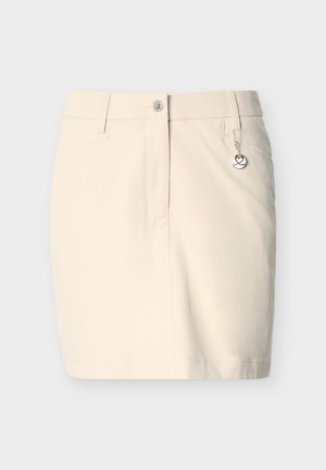 Jupe beige longueur genou avec une ceinture boutonnée, passants pour ceinture, poches latérales et un petit pendentif rond suspendu à la poche droite.