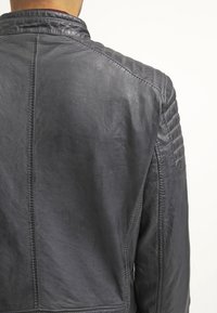 Sort læderjakke med quiltet tekstur på skuldrene, der har en høj krave og synlige sømme på ryggen.