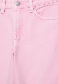 Részlet fény rózsaszín farmernadrágból, elöl gombbal, cipzáras sliccel, övbújtatókkal és fém szegecsekkel díszített első zsebbel.