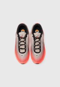 Lengvi tinkliniai sportbačiai, kurių spalvos gradientas pereina nuo smėlio iki ryškiai koralinės, su juodais raišteliais ir matomu Air Max logotipu.