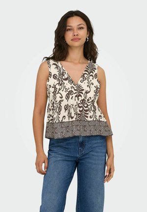Blusa senza maniche in tessuto crema con intricate fantasie floreali marroni e orlo geometrico. Design a V con una vestibilità comoda. Abbinata a jeans blu.