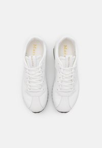 Baskets blanches à lacets avec semelles noires, vues de dessus, présentant la marque "Marc O'Polo" sur la languette et la semelle intérieure.