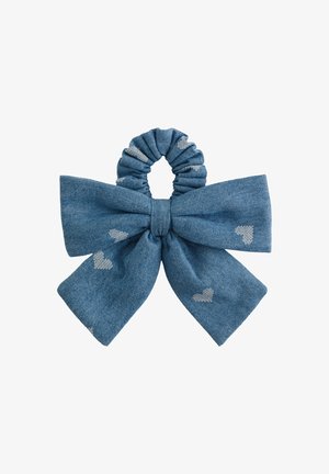 Coletero de tela azul con un lazo grande decorado con pequeños corazones blancos, aislado sobre fondo blanco.