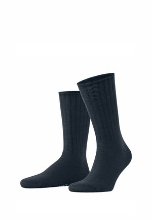 Paar schlichte schwarze, knielange Rippensocken, die aufrecht auf weißem Hintergrund stehen.