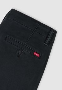 Μαύρο βαμβακερό παντελόνι με απαλό ύφασμα, που διαθέτει πίσω τσέπη, κλείσιμο με κουμπί και κόκκινη ετικέτα λογότυπου Levi's στο πλάι.