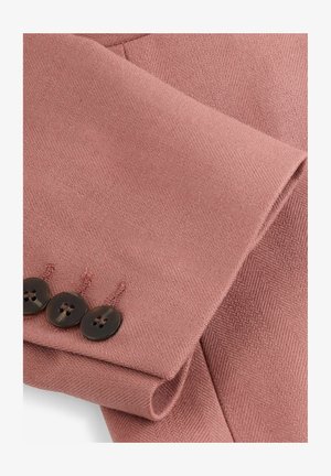 Blazer sartoriale in tessuto rosa pallido con finitura testurizzata. Caratterizzato da tre bottoni scuri sul polsino e bordi netti e affilati.
