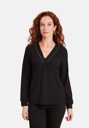 Zwarte blouse met lange mouwen en V-hals, met fijne witte stiksels langs de halslijn. Getextureerde stof met een ontspannen pasvorm.