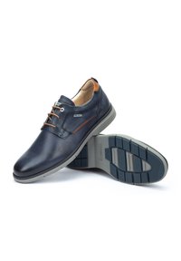 Chaussures en cuir bleu marine pour hommes avec des accents marron clair, bout rond, lacets stylés et semelle en caoutchouc texturé gris.