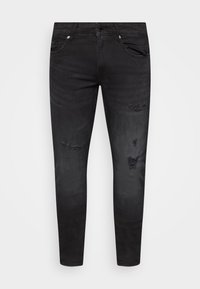 Jeans de mezclilla negra con un corte slim, áreas desgastadas y costuras en contraste. La tela tiene un ligero brillo y una textura suave.