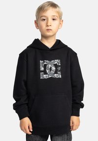 Zwarte hoodie van zacht materiaal, met een grafische print van schedels in het wit aan de voorkant. Inclusief een voorkant zak en ribgebreide manchetten.
