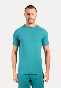 Turkusowa koszulka z krótkim rękawem, okrągłym dekoltem i rękawami raglanowymi. Gładka tekstura, minimalistyczny design i elastyczny materiał, idealny do aktywności fizycznej.