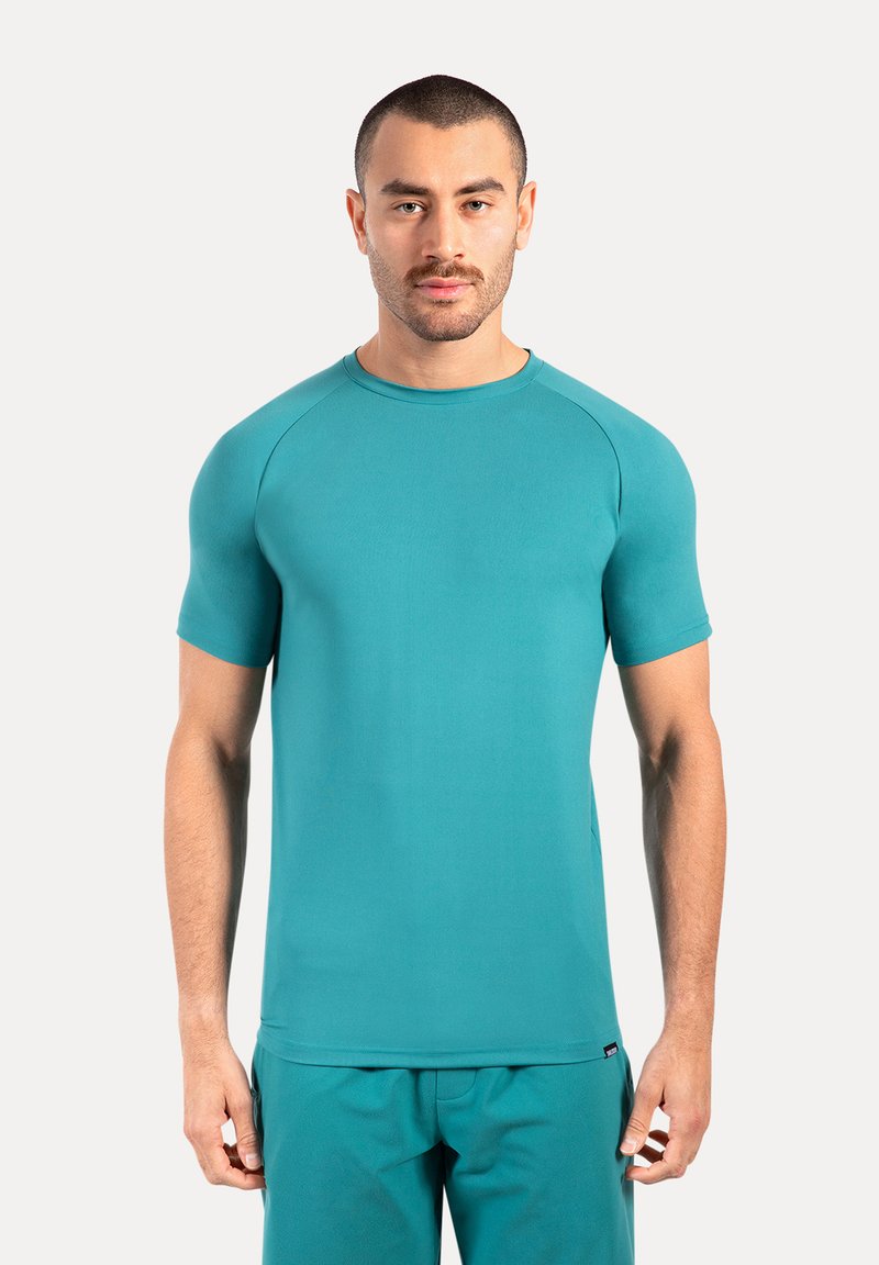 Turkusowa koszulka z krótkim rękawem, okrągłym dekoltem i rękawami raglanowymi. Gładka tekstura, minimalistyczny design i elastyczny materiał, idealny do aktywności fizycznej.