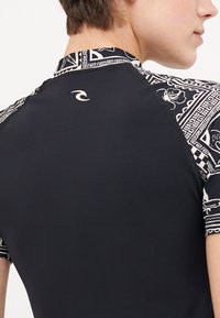 Short-sleeved wetsuit featuring a black body and patterned sleeves in white and black. Includes a small logo on the back collar.