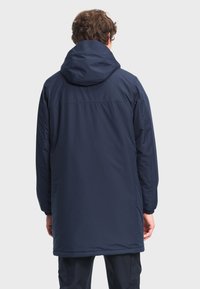 Marineblauwe, geïsoleerde jas met een capuchon en lange mouwen. Voorzien van elastische manchetten en een recht gesneden model, dat volledige dekking aan de achterkant biedt.