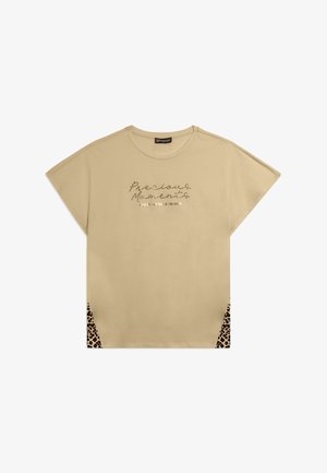 T-shirt beige à manches courtes avec panneaux latéraux imprimés léopard et inscription "Precious Moments" en cursive sur la poitrine.