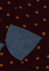 Dark maroon socks with small yellow polka dots and contrasting light blue heel patches in close-up view.