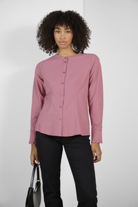 Chemise à manches longues, boutonnée, en rose doux, fabriquée en tissu lisse avec une coupe ajustée et un subtil détail de volants aux poignets.