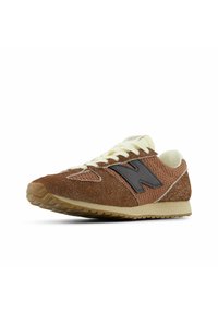 Brown suede and mesh sneaker with black "N" logo, cream laces, and a beige ridged sole angled left on a white background.