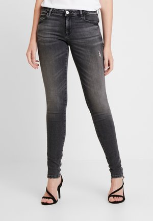 Kapeat farkut haalistuneessa mustassa denimissä, joissa on keskitason vyötärö, viisi taskua, kevyt kulutus ja yhdistetty mustiin remmillisiin korkokenkiin.