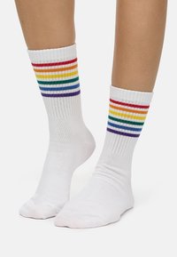 Weiße Knöchelsocken mit bunten Streifen in Rot, Orange, Gelb, Grün, Blau und Lila am oberen Rand. Rippstruktur, mittlere Dicke.