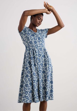 Robe en coton à motif floral bleu avec des manches courtes, décolleté en V et silhouette en A, présentant une taille froncée et une longueur au genou.