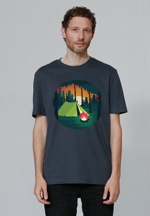 Donkergrijze katoenen T-shirt met een cirkelvormige grafische afbeelding van een tent, kampvuur en bomen, met kleuren van de zonsondergang op de achtergrond.