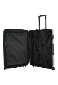 Maleta rígida con exterior plateado, asa retráctil, cuatro ruedas y un interior espacioso con forro negro y correas de compresión.