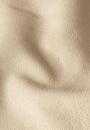 Primo piano di tessuto beige strutturato con grana fine e pieghe sottili, che mostra morbidezza e aspetto naturale.