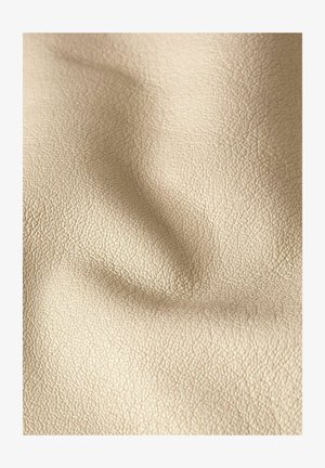 Primo piano di tessuto beige strutturato con grana fine e pieghe sottili, che mostra morbidezza e aspetto naturale.