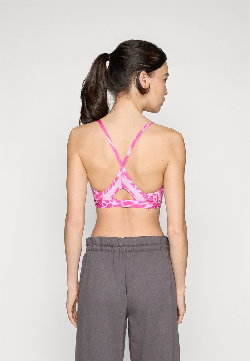 Rosa Sport-BH mit floralem Muster, mit überkreuzten Trägern im Rücken und einem Cut-out-Detail. Das Material scheint glatt und elastisch zu sein.