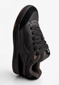 Crna sportska cipela izrađena od brušene kože i mrežastih materijala, s teksturiranim gornjim dijelom, okruglim nožnim prstom, vezicama i smeđim gumenim potplatom.