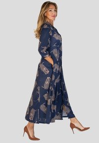 Granatowa sukienka maxi w leoparda, wykonana z lekkiego materiału. Posiada długie rękawy, boczne kieszenie oraz zwiewną sylwetkę.