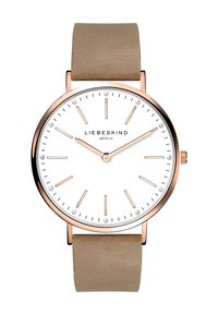 Montre ronde avec un cadran blanc, des accents en or rose et un bracelet en tissu beige. Dispose de marqueurs ressemblant à des diamants et de aiguilles des heures et des minutes minimalistes.