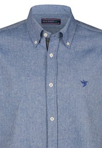Camisa de botones de patrón en espiga azul, con cuello, botones blancos y un pequeño logotipo de un pájaro azul en el pecho.