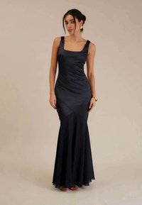 Vestido de noite em cetim azul marinho, ajustado ao corpo, com decote quadrado, corpete franzido e bainha evasê, apresentando uma silhueta elegante e embelezamentos mínimos.