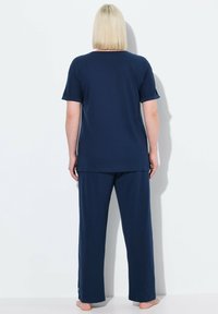 Navyblauwe katoenen pyjama-sets met een T-shirt met korte mouwen en een ronde hals, en losse broek met zijstrepen. Zachte, gladde textuur.